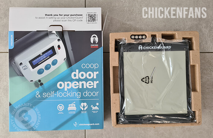 Chickenguard chicken coop door shipping box with the content of the box: the door wrapped in plastic, sitting fixed in rigid carton