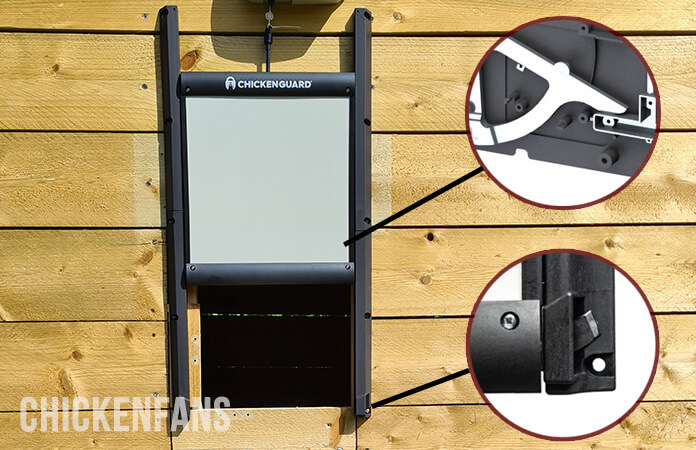 Chicken coop with a ChickenGuard Coop door installed, showing the details of the locking mechanism on the inside and how the lock anchors hook into the receivers of the guiding rails