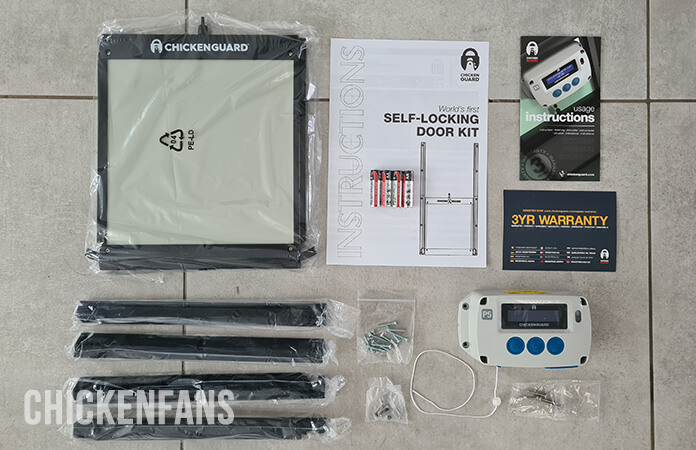 Overview of all the contents that ship in the box when you order a combi box of door and opener: the rails, the door, three sets of screws, batteries, a warranty card, instructions of the automatic door opener, and instructions of the self-locking door kit