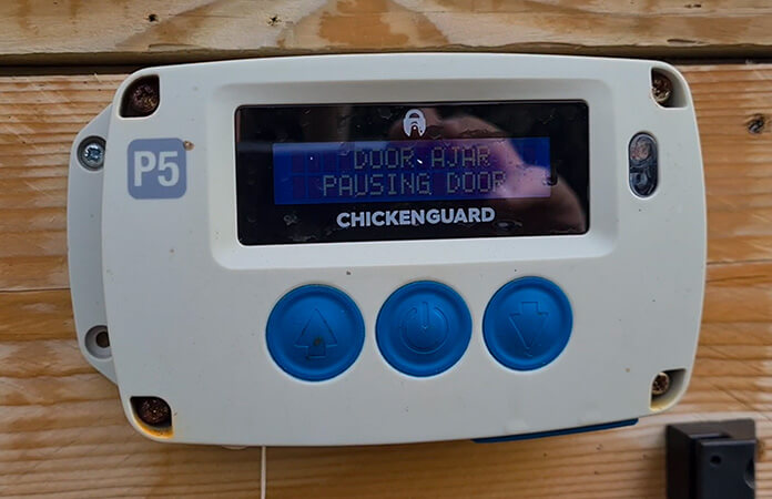 ChickenGuard door opening unit in self-diagnosis mode showing the message DOOR AJAR PAUSING DOOR to indicate that it detected a preemtive stop of the automatic chicken coop door