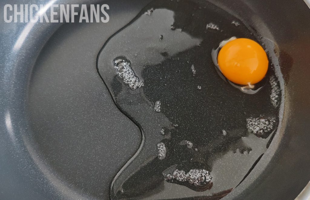 a chicken egg with watery egg whites in a frying pan