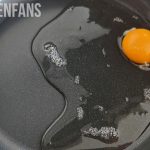 a chicken egg with watery egg whites in a frying pan